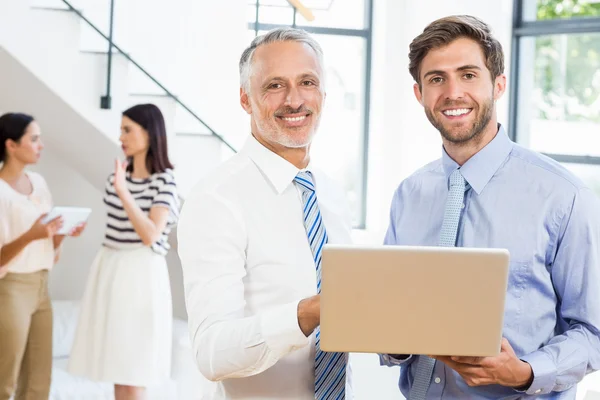 Two businessmen holding laptop