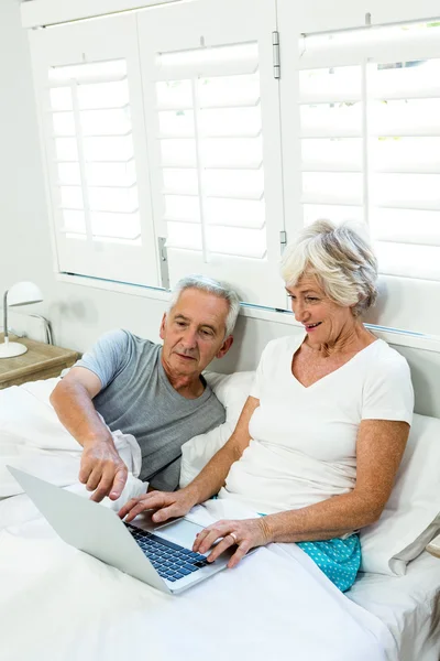 Senior couple using laptop on bed