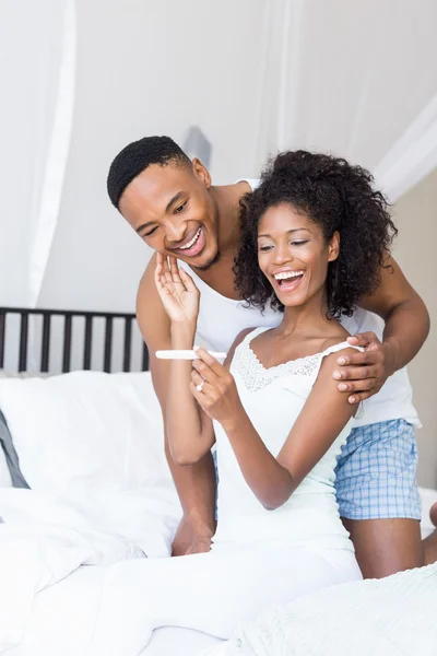 Couple looking at pregnancy test on bed