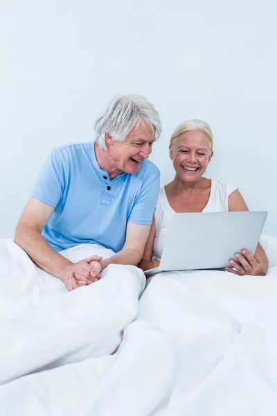 Senior couple using laptop on bed