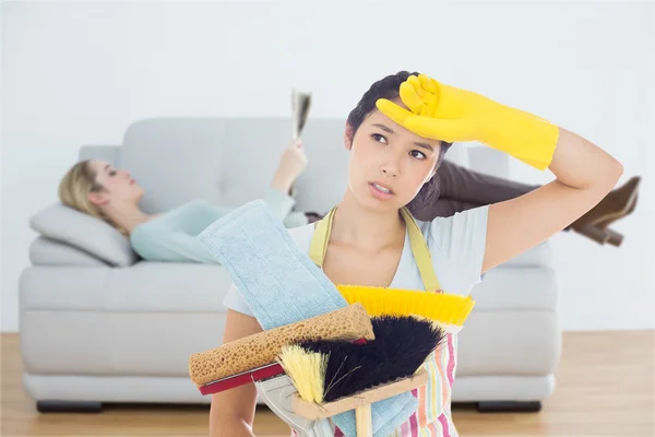 Weary woman holding cleaning tools