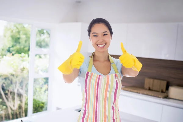 Happy woman giving thumbs up in rubber gloves