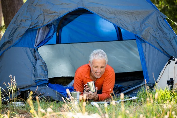 Mature man laying and holding a mug