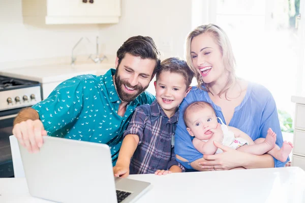 Parents and kids using laptop in living room