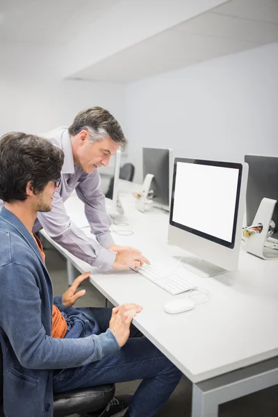 Computer teacher assisting a student