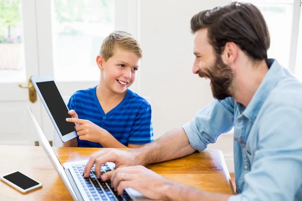Father and son using laptop and digital tablet