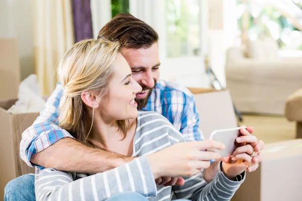 Couple using mobile phone in living room