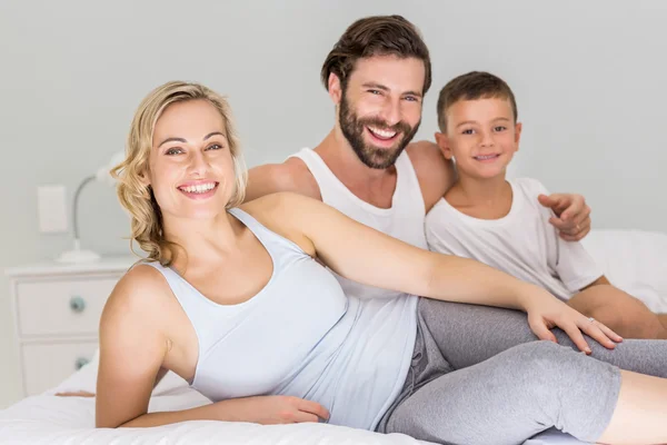 Parents and son sitting on bed in bedroom