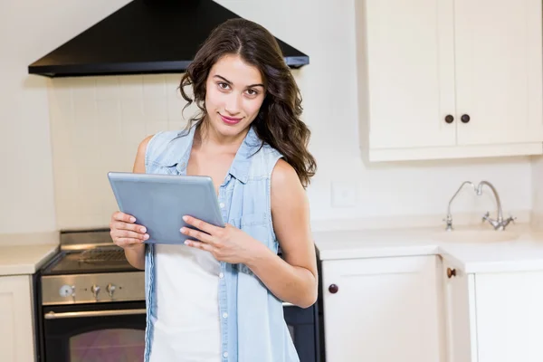 Young woman using digital tablet in kitchen