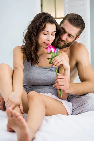 Man offering a rose to woman on bed