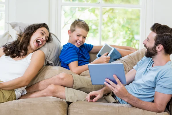 Parents and son sitting on sofa and using digital tablet