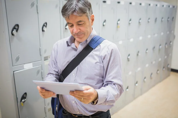 Professor using digital tablet in locker room