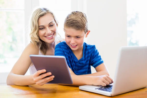 Happy mother and son using laptop and digital tablet