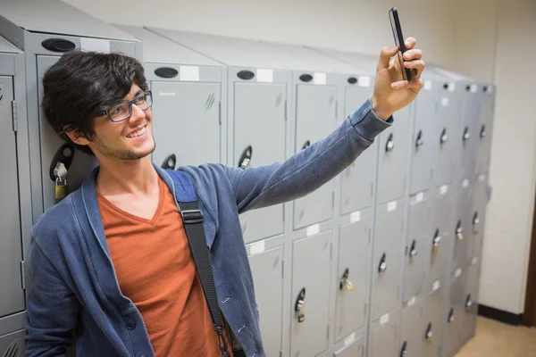 Smiling student taking selfie in locker room