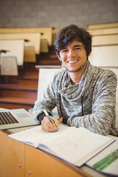 Portrait of young student sitting at desk reading notes