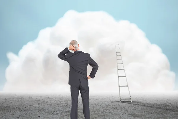 Businessman standing against giant cloud