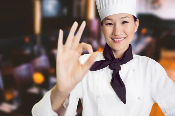 Smiling female cook gesturing okay sign