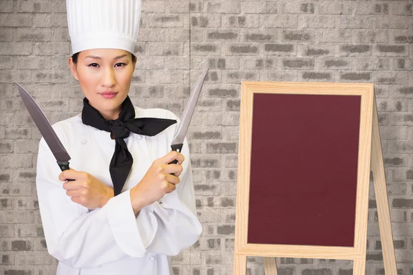 Confident female cook holding knives