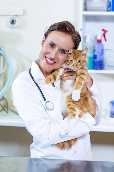 Portrait of woman vet giving a hug to a cat