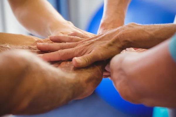 Seniors and fitness instructor putting their hands together