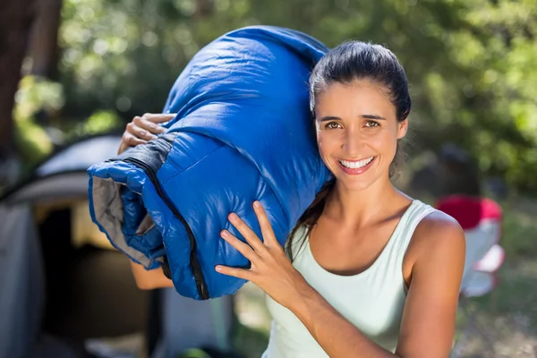 Woman smiling and holding a sleeping bag