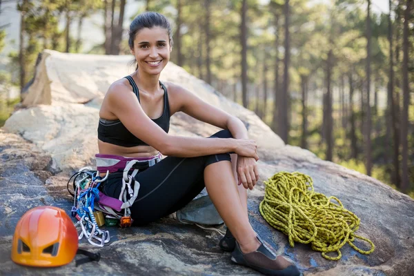 Woman smiling and sitting with climbing equipment
