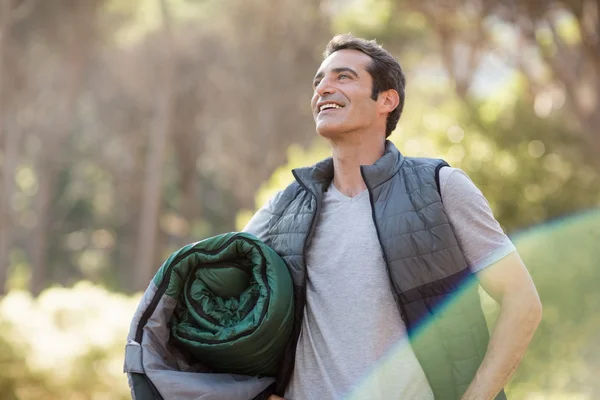 Man smiling and holding a sleeping bag