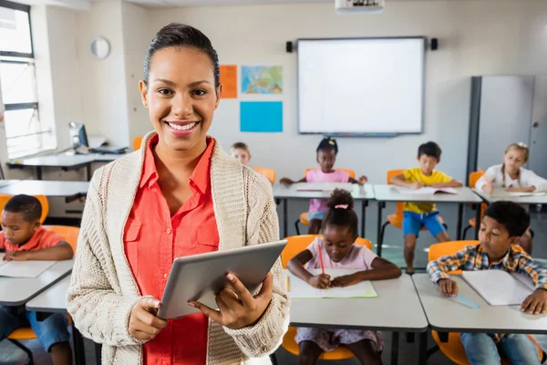 Teacher posing in front of class with tablet pc