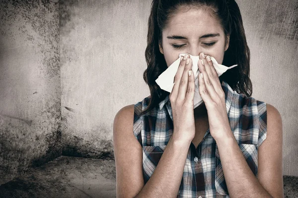 Beautiful woman sneezing in a tissue