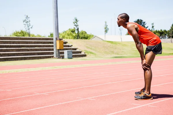 Tired athlete standing on running track