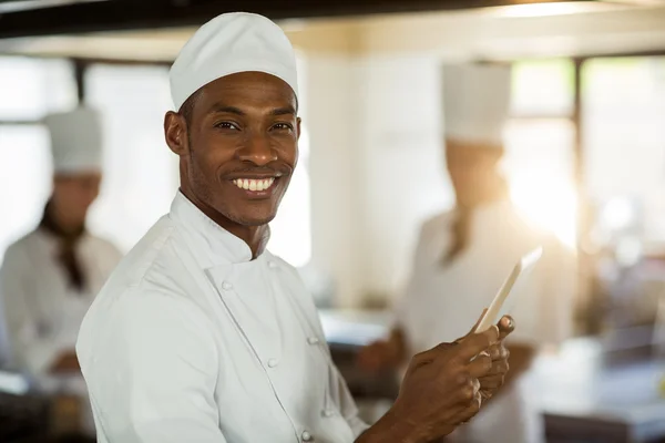 Smiling chef using digital tablet