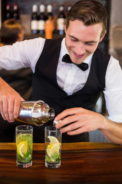 Bartender pouring drink from shaker to glass