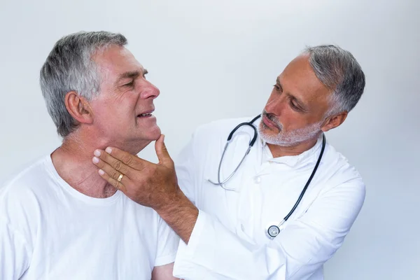 Male doctor examining senior mans neck