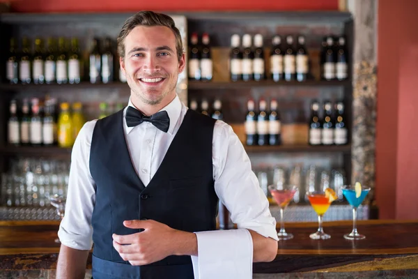 Confident waiter in front of bar counter