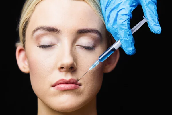 Woman receiving botox injection on lips