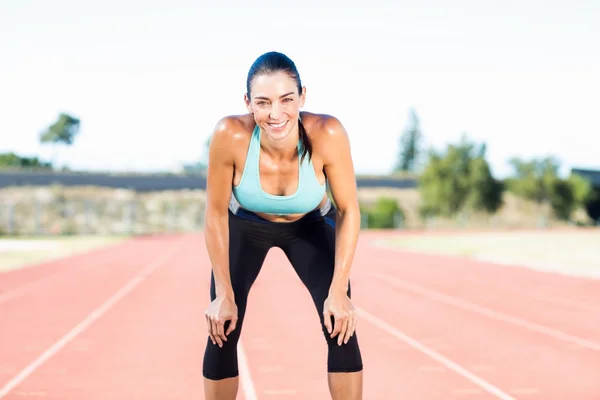 Tired female athlete standing on running track