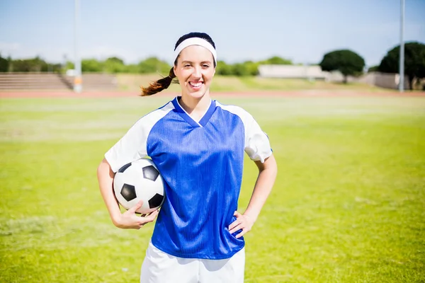 Happy soccer player standing with a ball