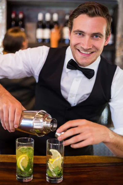 Bartender pouring drink from shaker to glass