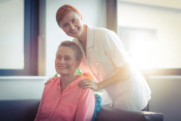 Portrait of happy nurse and patient in living room