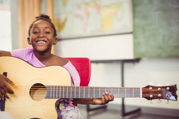 Schoolgirl playing guitar in classroom