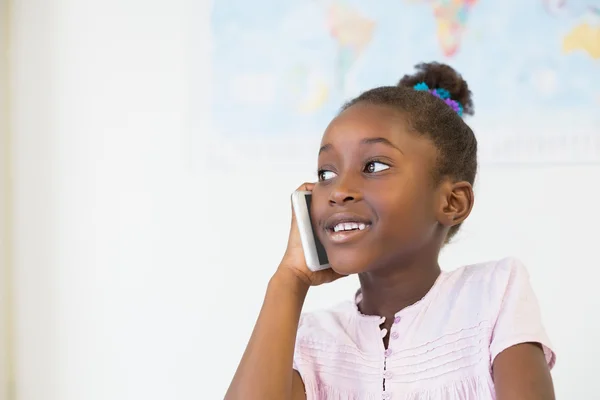 Schoolgirl talking on phone in classroom