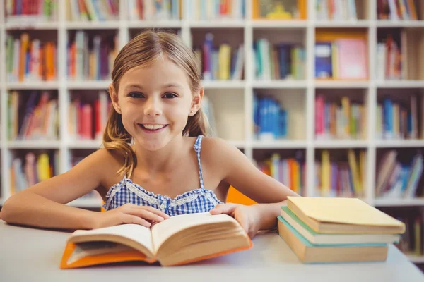 School girl reading book in library