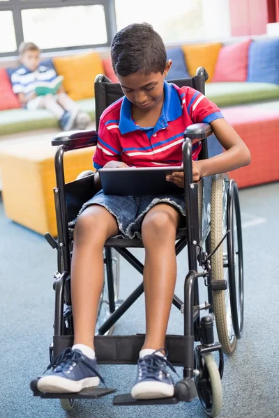 Disabled schoolboy on wheelchair using tablet