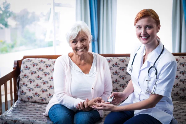 Doctor testing a patients glucose level using a digital glucometer