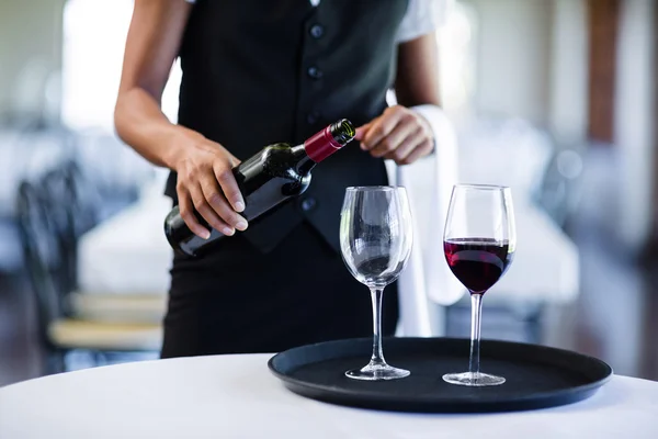 Waitress pouring red wine in glass