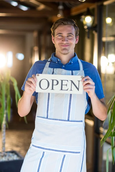 Smiling chef holding open sign