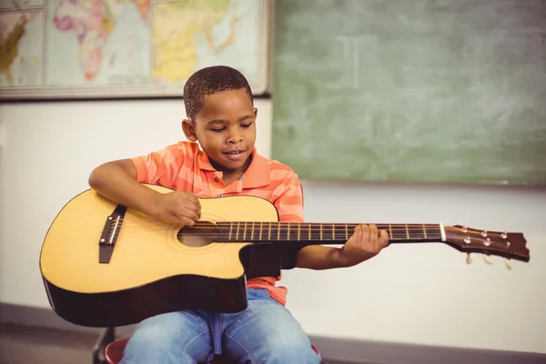 Schoolboy playing guitar in classroom