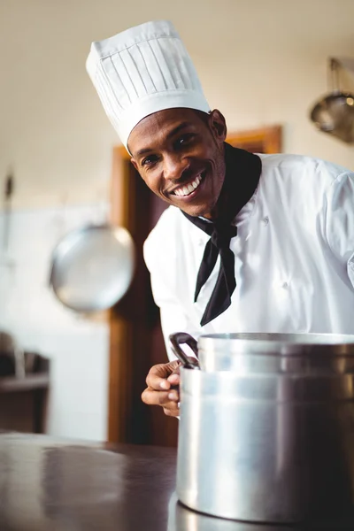 Chef in kitchen holding cooking pot