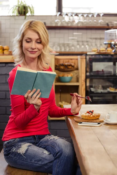 Woman reading book eating cake