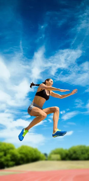 Woman jumping against athletics field